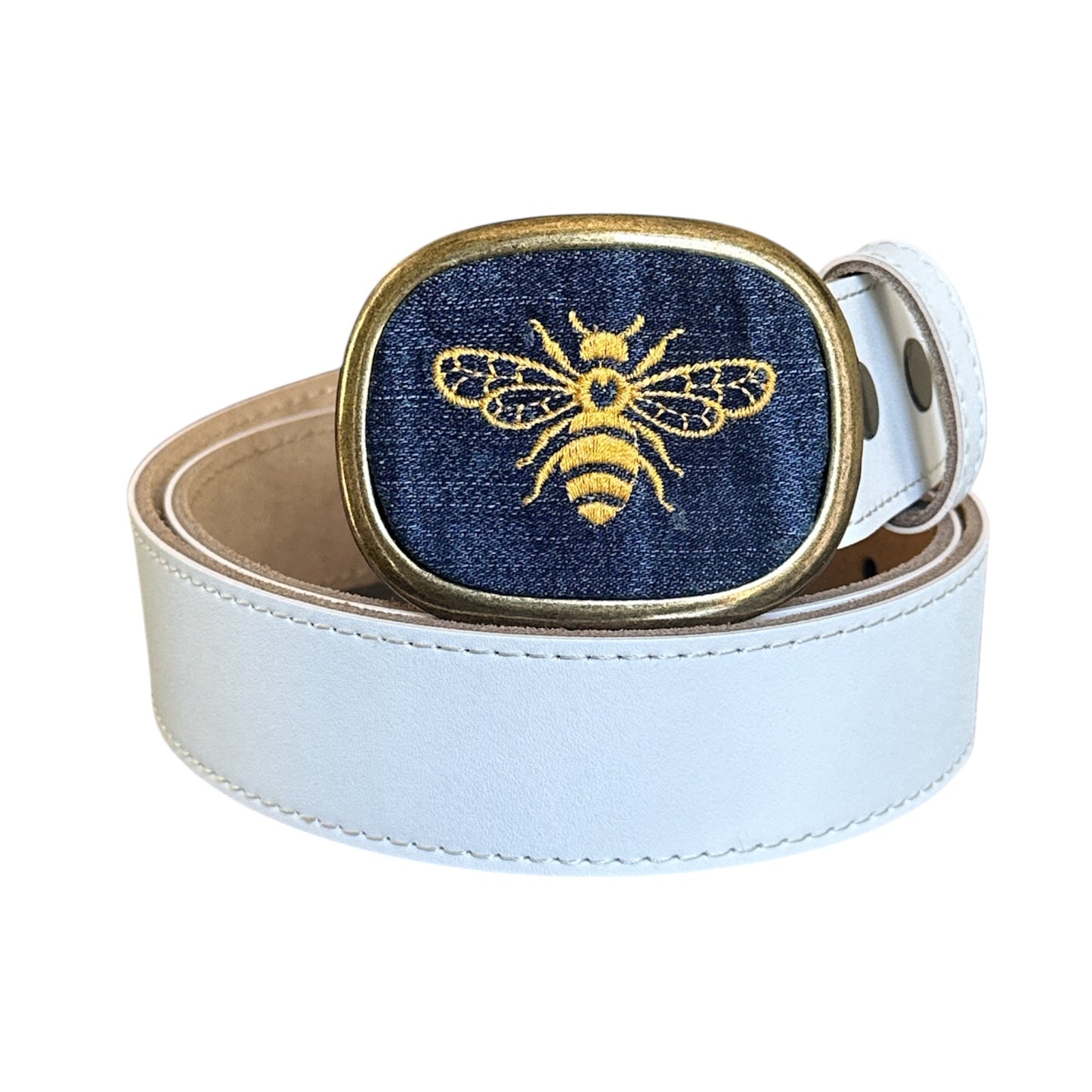 A bumble bee embroidered on denim set in an antique brass belt buckle with a white belt. 